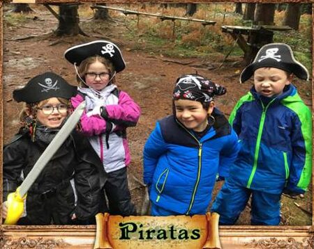 Quatre enfants déguisés en pirates avec chapeaux et sabres dans la forêt, encadrement Piratas