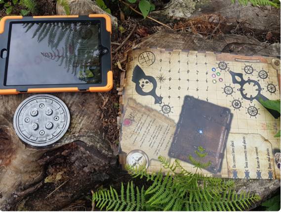 Tablette interactive et carte au trésor avec cadenas posés sur une souche en forêt